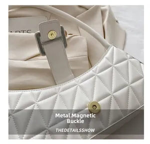 Détail du fermoir magnétique doré sur le sac à bandoulière blanc en similicuir matelassé