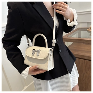 Close-up of cream bow handbag with silver hardware and textured leather finish