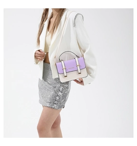 Detail of a purple and white crossbody bag with fashion text shown on a model