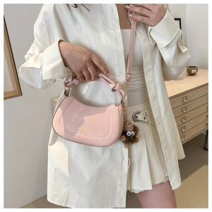 Detail of pink crescent bag with knotted handle and brown plush charm accessory