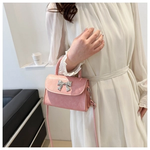 Detail of pink bow handbag showing textured leather and silver metallic ribbon