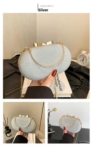 Detail of silver sequined evening clutch bag with golden bow clasp and chain strap
