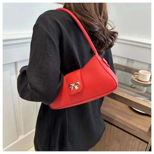Détail du sac à bandoulière en cuir PU rouge avec fermoir doré en forme de nœud sur mannequin