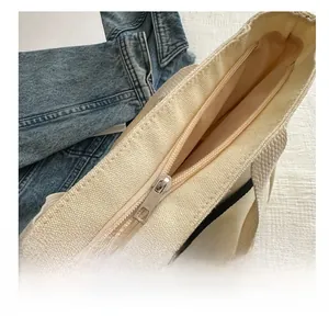Detail of silver metal zipper and smooth stitching on off-white canvas tote bag