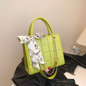 Quilted lime green handbag with silk scarf detail and gold chain strap on display
