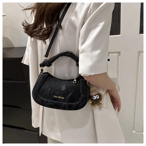 Detail of black marble patterned half-moon handbag with gold zipper and plush monkey charm