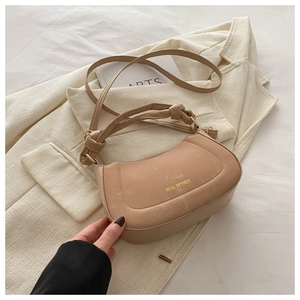 Detail of beige crescent bag featuring a knotted handle and Tidal Dryness lettering