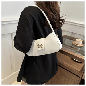 Détail d'un sac à bandoulière en cuir blanc avec boucle de nœud doré sur le rabat