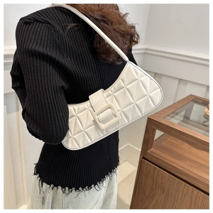 Gros plan d'un sac à bandoulière matelassé blanc avec une grande boucle carrée portée