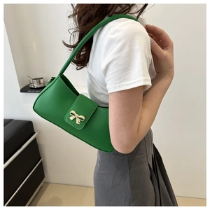 Detail of green PU leather baguette bag with a bright gold bow-shaped metal buckle