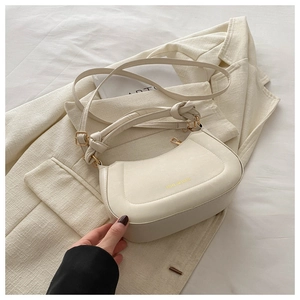 Detail of cream half-moon leather bag with knot handle and gold zipper on blazer