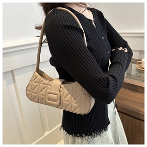 Détail du sac baguette beige matelassé avec une grande boucle carrée et une bandoulière