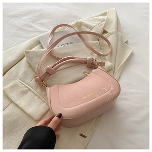 Detailed view of pink matte handbag with gold logo, knotted handle and zipper texture