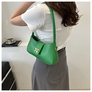 Détail d'un sac sous le bras vert vif en similicuir avec un nœud doré métallique élégant