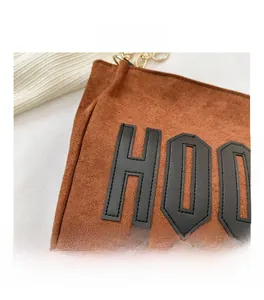Gros plan sur un sac cabas en daim marron avec lettres noires et anse en chaîne dorée