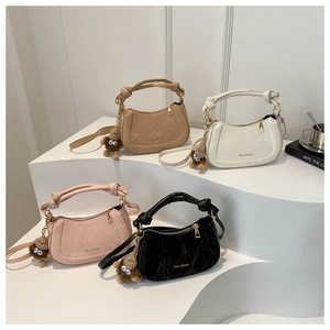 Group of four colored crescent handbags with knot handles and plush monster charms