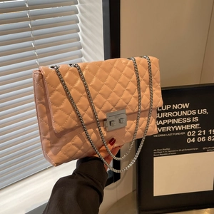 Pink quilted crossbody bag with silver chain strap and metal lock shown in lifestyle setting