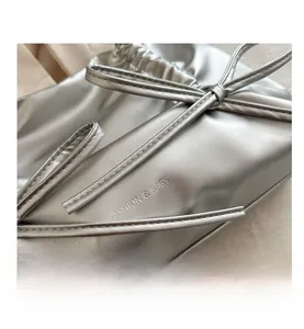Detail of silver metallic pleated bag with bow tie and engraved Fashion text