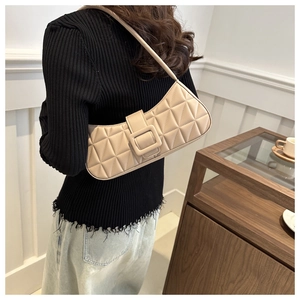 Détail de sac porté épaule beige matelassé avec boucle carrée sur un mannequin