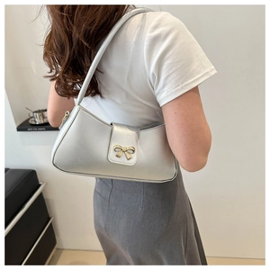 Détail du sac à bandoulière argenté avec élégant fermoir en nœud doré en métal