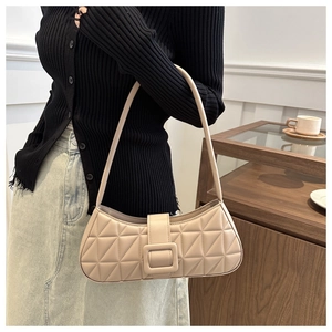 Détail du sac baguette beige montrant la texture matelassée et la boucle carrée décorative