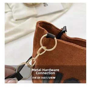 Détails de la chaîne dorée et de la bandoulière sur un sac cabas en daim marron