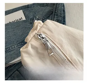 Macro shot of smooth silver metal zipper on off-white nylon ruched bag with durable fabric