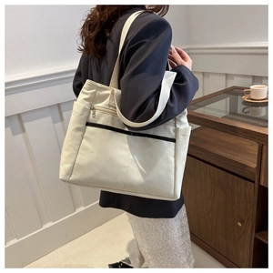 Dettaglio della borsa tote in tela bianco sporco con tasca frontale zip e scomparto laterale