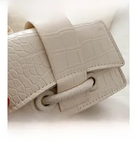 Detail showing creamy white crocodile pattern leather texture and bronze metal ring hardware