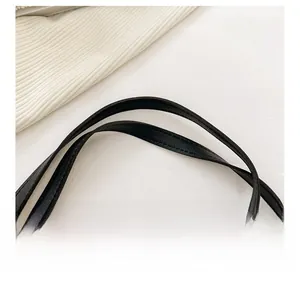 Détail de la poignée en cuir noir avec double couture parallèle sur un sac en toile