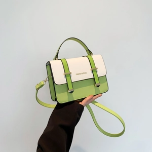 Green and white minimalist crossbody bag with gold hardware shown in a hand-held view