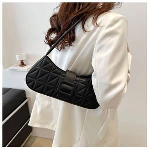 Vue détaillée d'une femme portant un sac baguette noir matelassé avec grande boucle