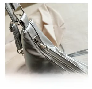 Close-up of smooth metal zipper and D-ring buckle on silver metallic pleated bag