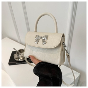 Detail of cream bow-knot crossbody bag with polished silver buckle and leather texture