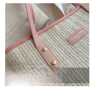 Detail of cross-woven straw tote with pink faux leather handle and gold rivet reinforcement