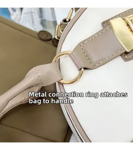 Detailed macro view of golden metal ring connecting handle to bicolor leather Boston bag