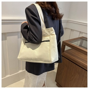 Dettaglio di una grande borsa tote in tela beige con strisce nere su una modella