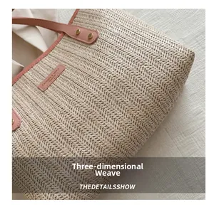 Detail of woven straw tote bag featuring terracotta leather trim and metal rivets