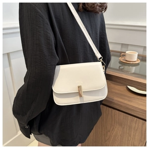 Detail of minimalist creamy white leather crossbody bag with a golden metal buckle clasp