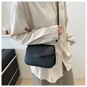 Side view of a black matte leather saddle bag worn with a casual minimalist outfit