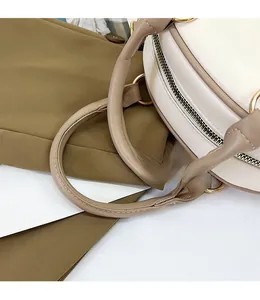 Detail of soft cream leather handle with reinforced stitching and gold metal ring