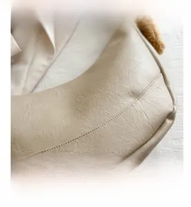 Detail of beige crescent shoulder bag showing premium faux leather texture and stitching