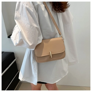 Detail of minimalist beige PU leather crossbody bag featuring a golden rectangular clasp