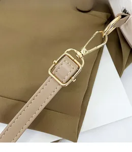 Detail of adjustable beige leather shoulder strap with golden metal swivel hooks