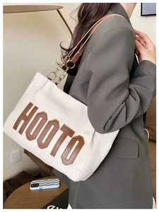 Détail du sac cabas en daim givré avec lettrage HOOTO en cuir brun et bandoulière chaîne