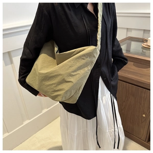 Detail of soft olive nylon tote bag showing its slouchy texture and wide shoulder strap