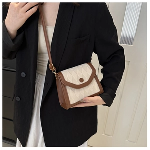 Detail of vintage beige quilted crossbody bag with brown leather trim and round buckle