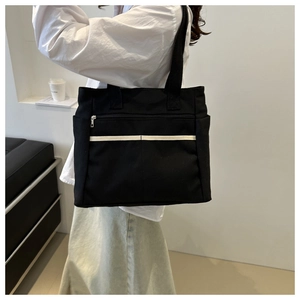 Dettaglio della borsa tote in tela nera con striscia bianca e tasca con zip