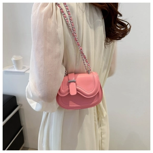 Close-up of pink mini saddle bag with wavy edge design and silver chain strap on model