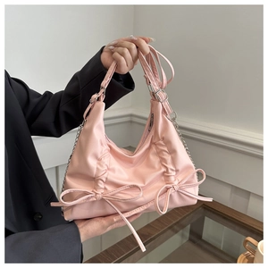 Close-up of pink bow tote bag with pleated texture and stylish metal chain strap